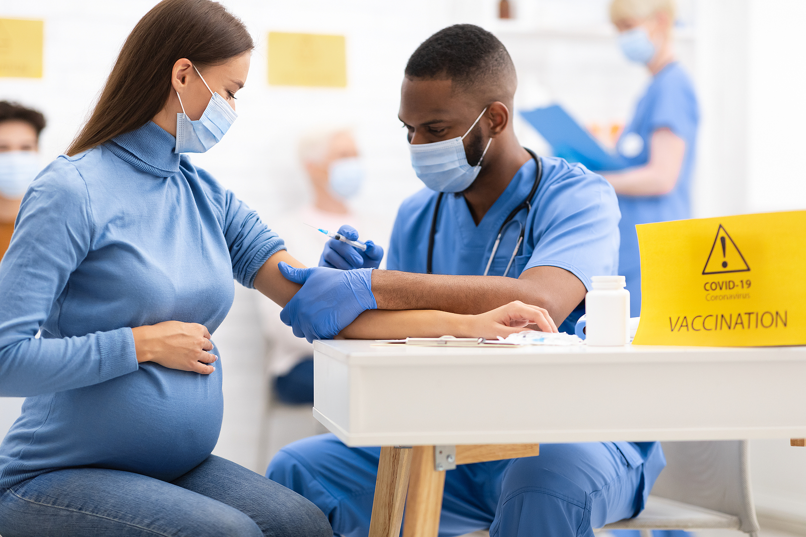 Pregnant women receiving a Covid vaccine from a doctor.